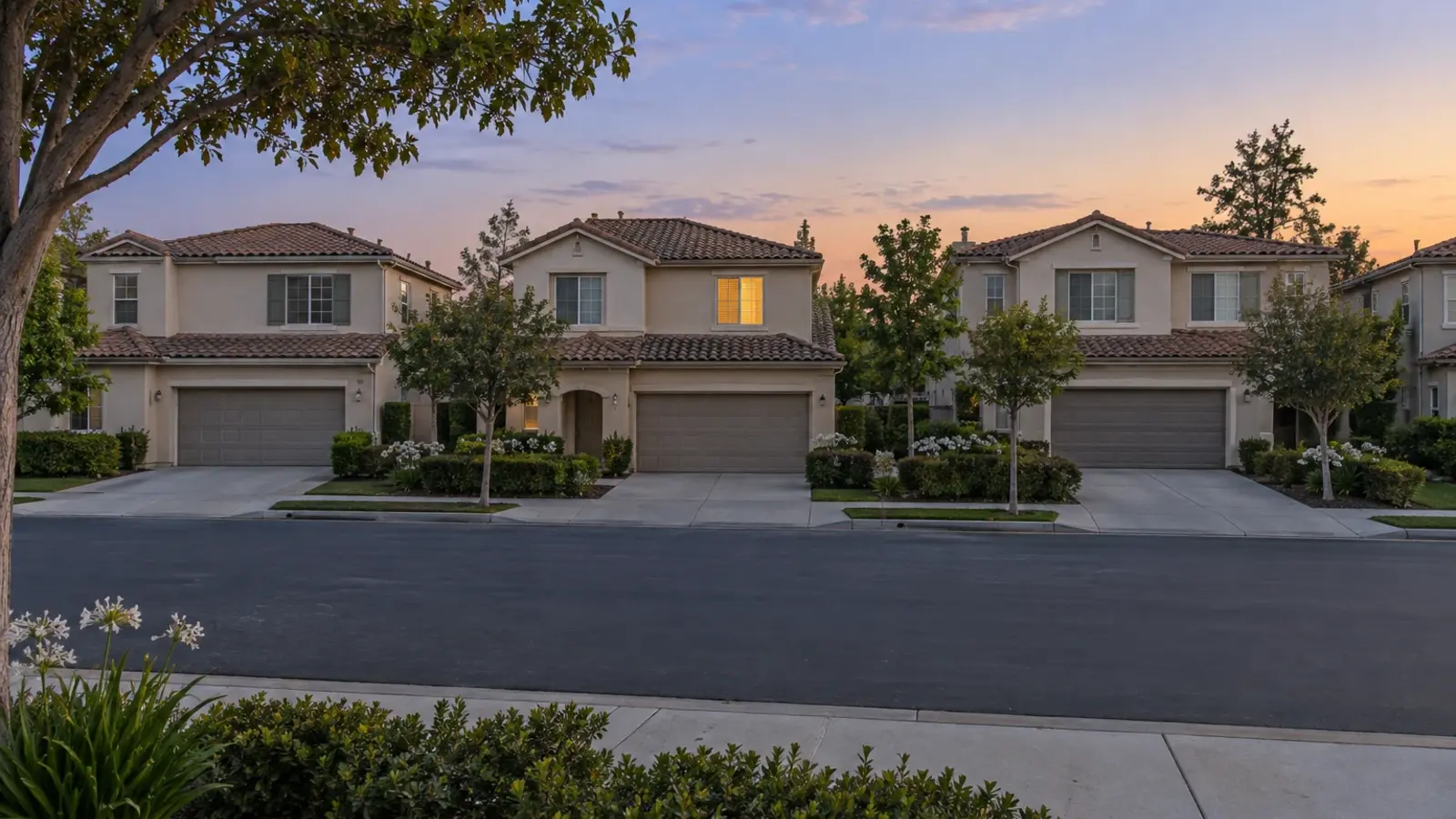 A row of matching two story stucco homes in a planned community at twilight, one window lit, Mission Viejo CA